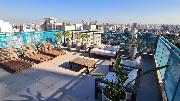 A rooftop terrace with wooden lounge chairs, a small table, and potted plants. - TrevizZo N.urban Pinheiros (São Paulo)