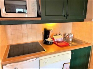 A compact kitchen with a microwave, a sink, and a dish rack.