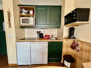 Una cocina compacta equipada con microondas, cafetera y lavavajillas.