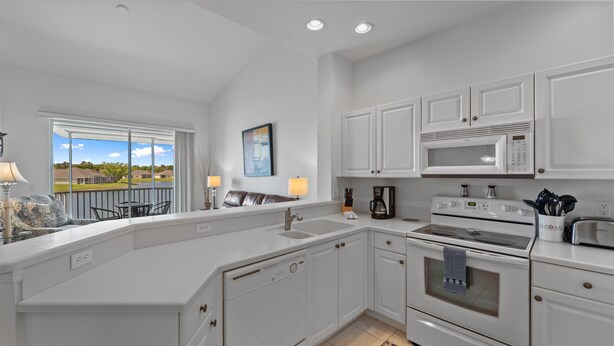 A modern kitchen with white cabinetry, a large island, a built-in oven, and a microwave. - Lakeview Lanai in Fort Myers! Gated community with resort like amenities!!! (Fort Myers)