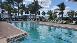 A swimming pool with clear water, surrounded by palm trees and lounge chairs. - Lakeview Lanai in Fort Myers! Gated community with resort like amenities!!! (Fort Myers)