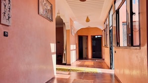 A hallway with a tiled floor, a hanging light fixture, and a door at the end.