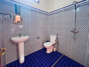 Un bagno con parete rivestita di piastrelle decorate, un lavandino, un WC e una doccia.