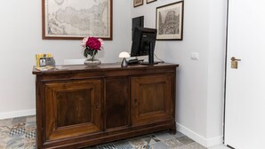 A reception desk with a map, framed pictures, and a vase with flowers. - Malu Suites (Messina)