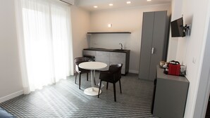 A compact kitchen with a white countertop, two chairs, and a small table. - Malu Suites (Messina)