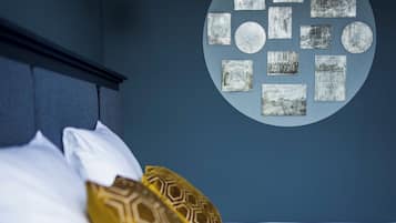 A bed with white and patterned pillows, a circular wall art piece, and a hanging light fixture.