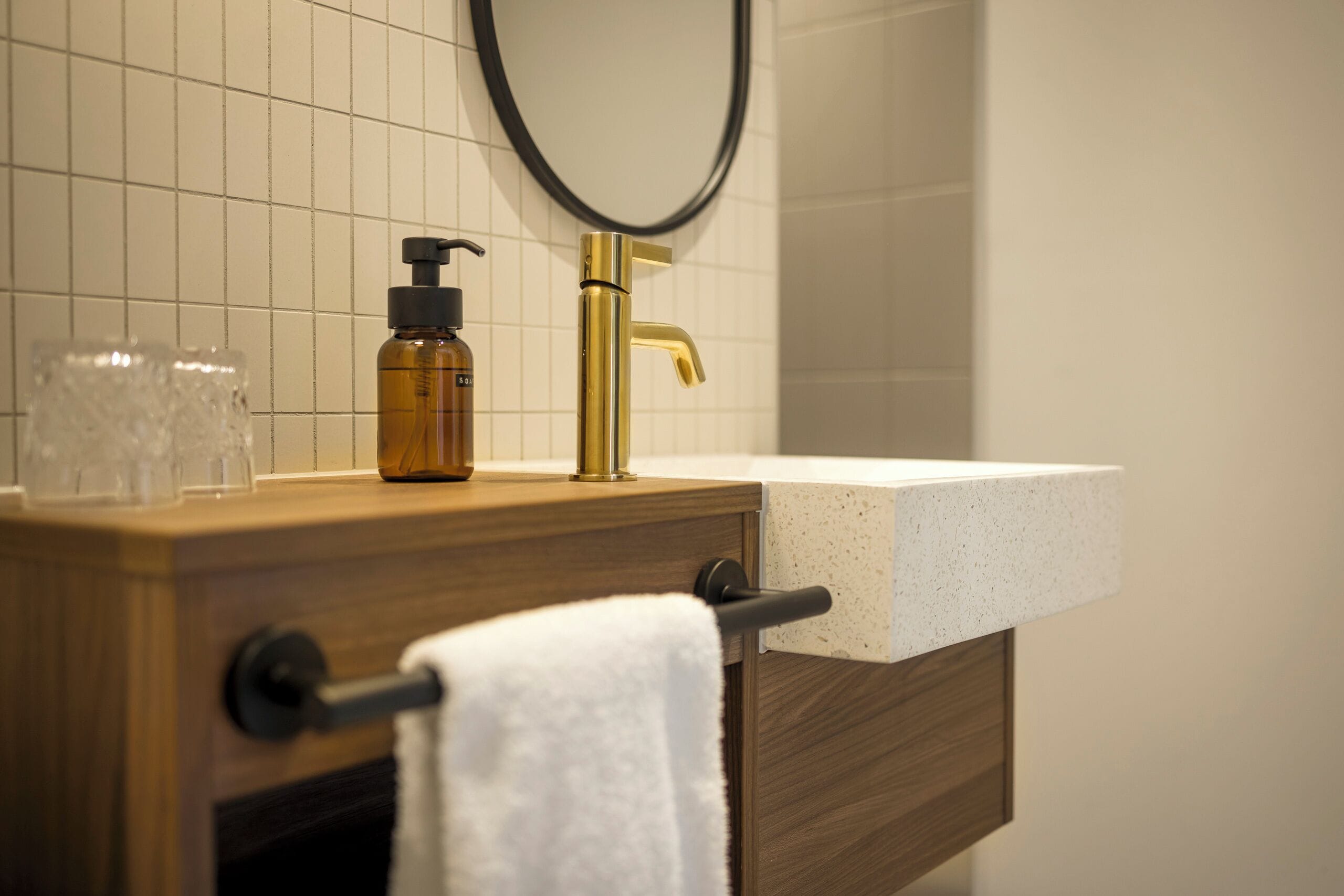 A bathroom vanity with a wooden countertop, a gold faucet, and a white sink.