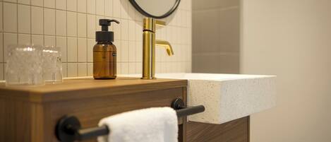Un tocador de baño con encimera de madera, grifo dorado y lavabo blanco.