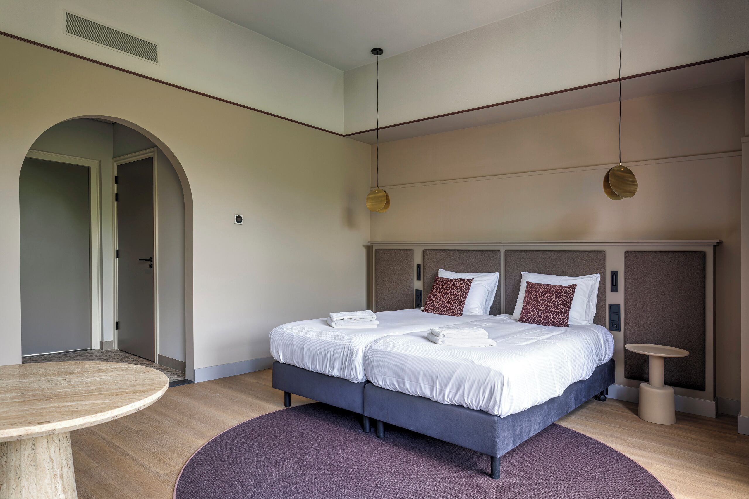 Une chambre d’hôtel moderne avec un grand lit, une table ronde et une petite table d’appoint.