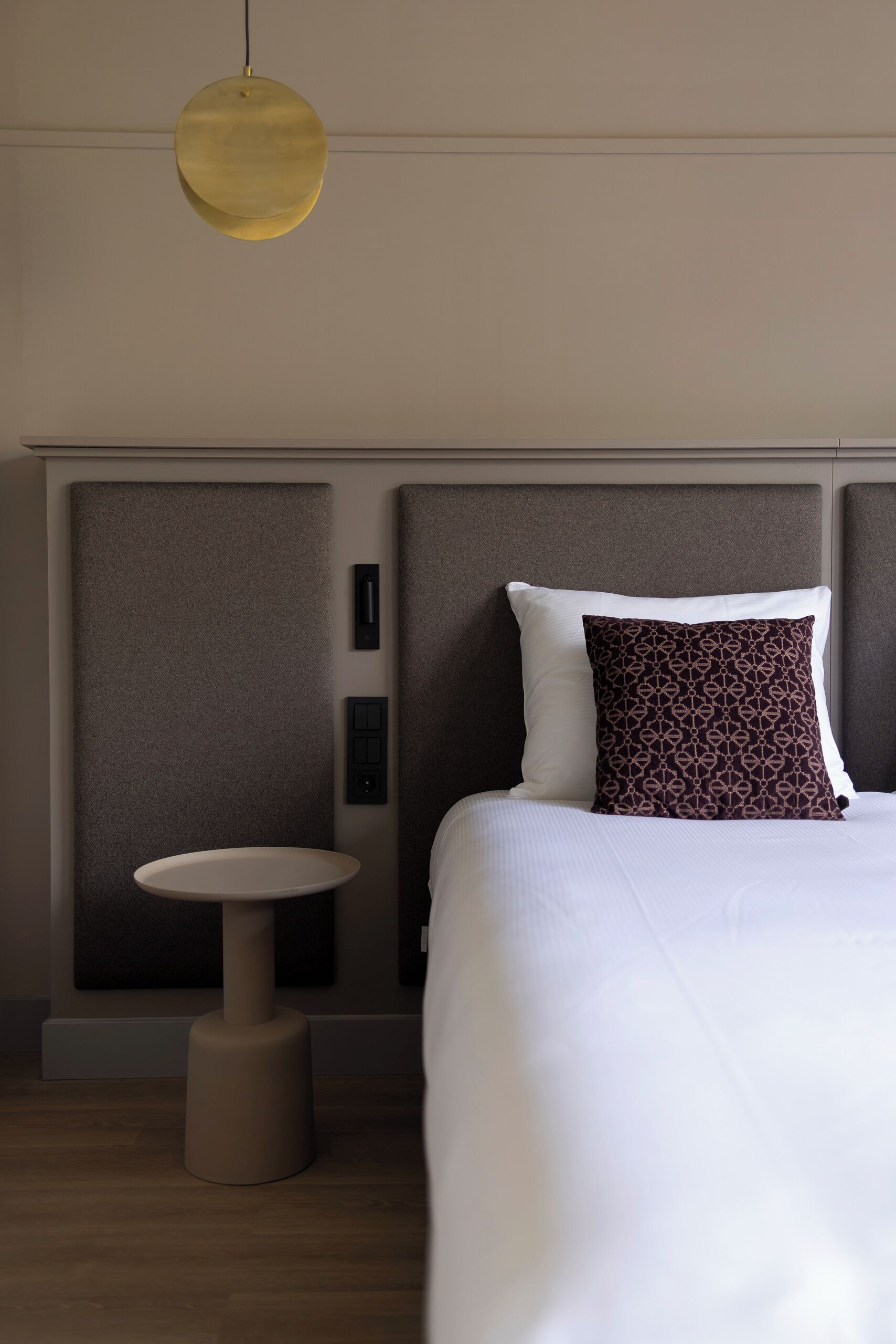 Een hotelkamer met een bed, een ronde tafel en een hanglamp.