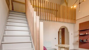A staircase with wooden railings, a round table, and a sofa in a modern interior. - SEPHS Hotel (Sittard)