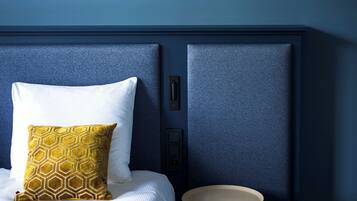 A bedroom with a bed, a bedside table, and a hanging light fixture.
