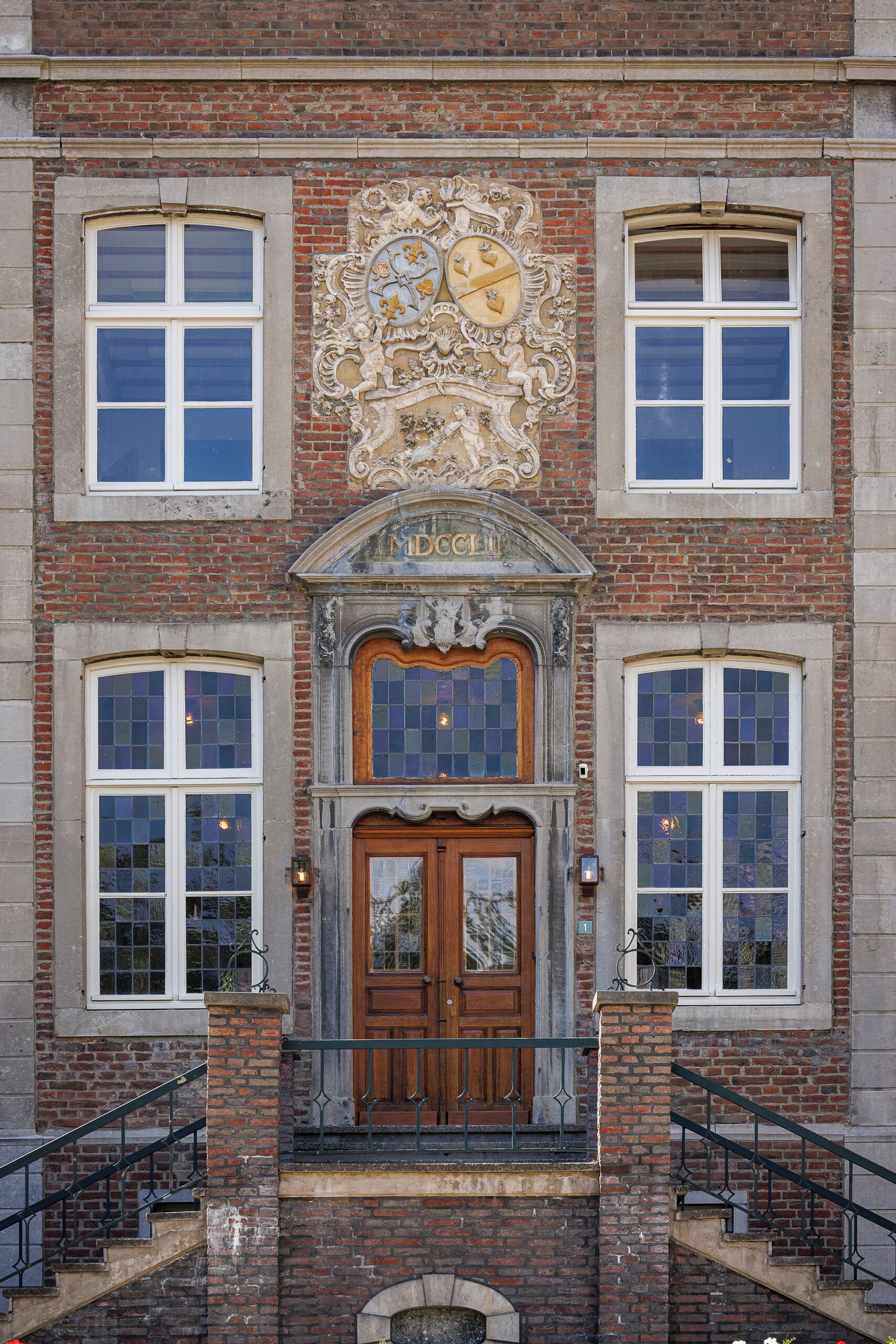 Un edificio con una entrada destacada, un escudo decorativo sobre la puerta y fachada de ladrillo.