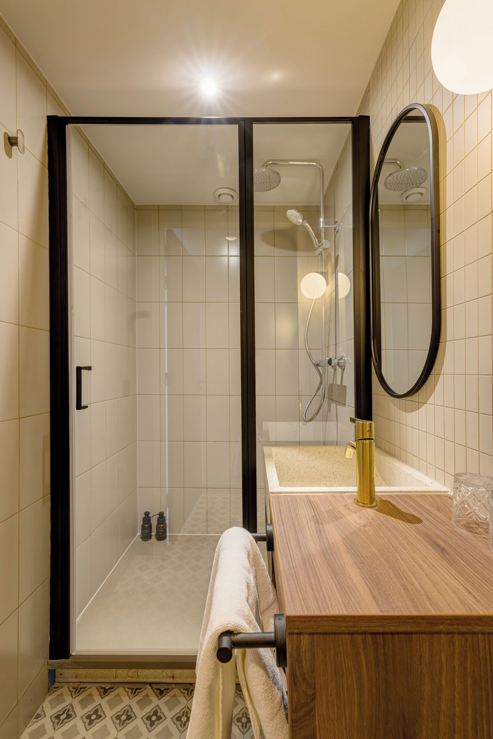 Un baño moderno con ducha de vidrio, tocador de madera y un espejo grande.