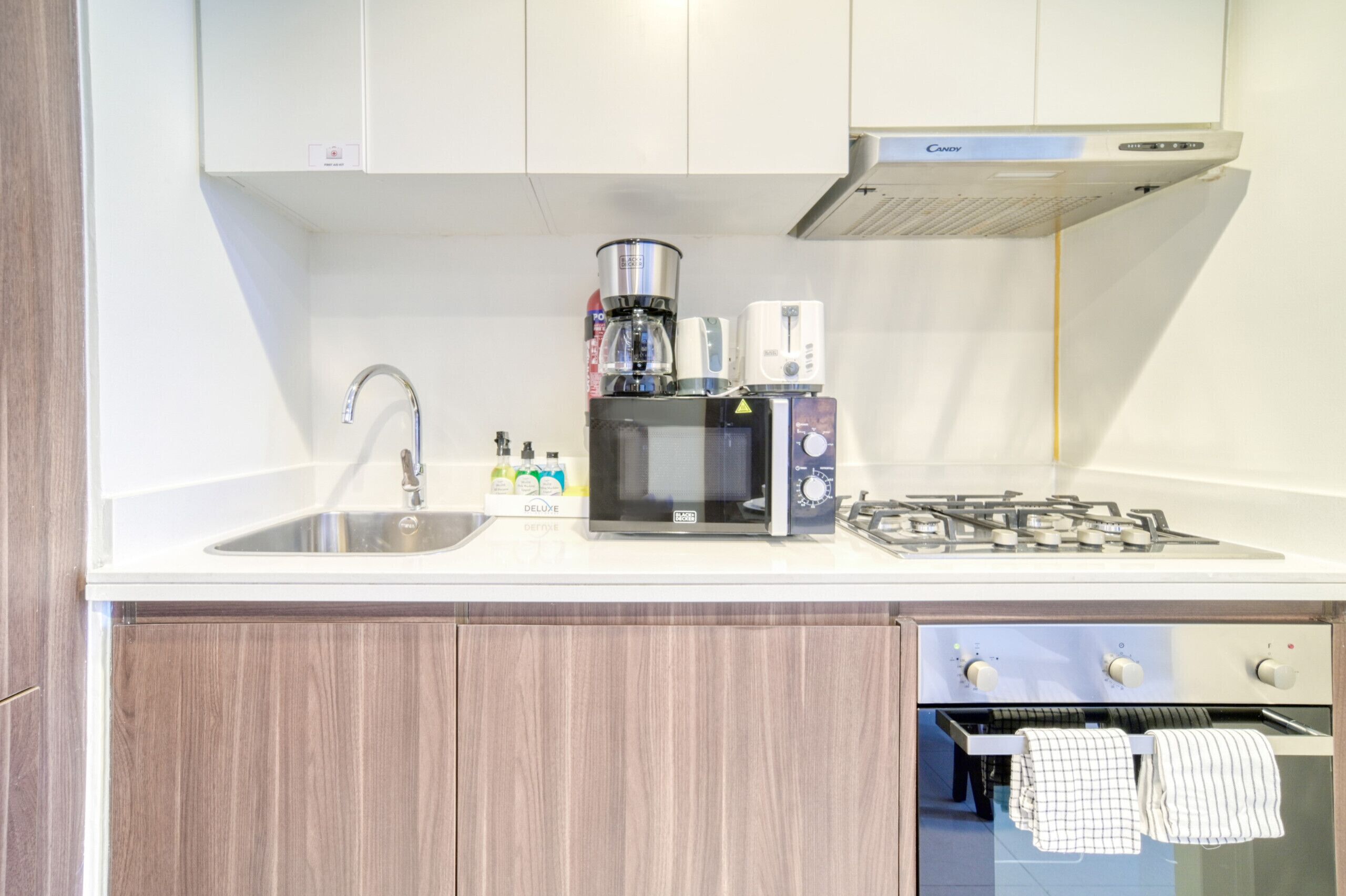 Une cuisine moderne équipée d’une cuisinière à gaz intégrée, d’un four à micro-ondes et d’une machine à café.