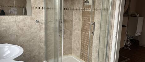 A modern bathroom with a glass-enclosed shower, a white sink, and a mirror.