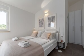 Quarto moderno com duas camas, uma mesa de cabeceira, um criado-mudo e um guarda-roupa.