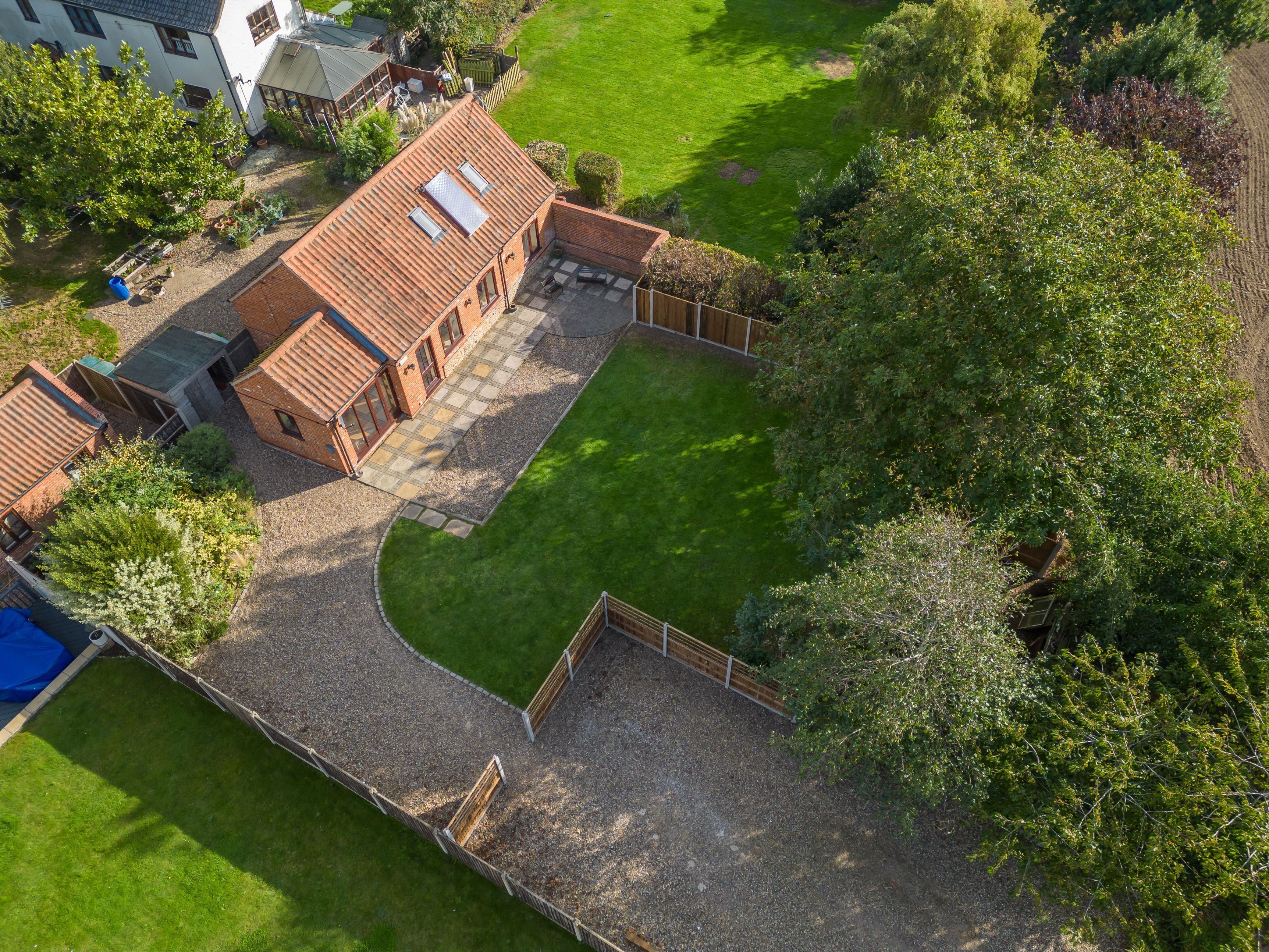 Luchtbeeld van een woonhuis met een stenen huis, een verzorgd gazon en een omheind tuingedeelte.