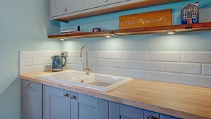 A kitchen with a double sink, wooden countertop, and light blue cabinets. - The Peanut | East Ruston Cottages (Happisburgh)