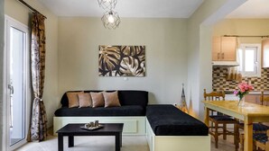Una sala de estar con un sofá, una mesa de comedor y una cocina al fondo.