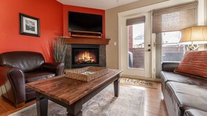Een woonkamer met een open haard, leren bank en een televisie.
