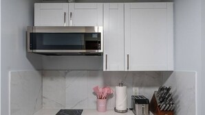 Een kleine keuken met een magnetron, een broodrooster en een messenblok op het aanrecht.