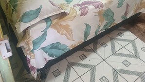 A small room with a bed, a curtain, and a tiled floor.