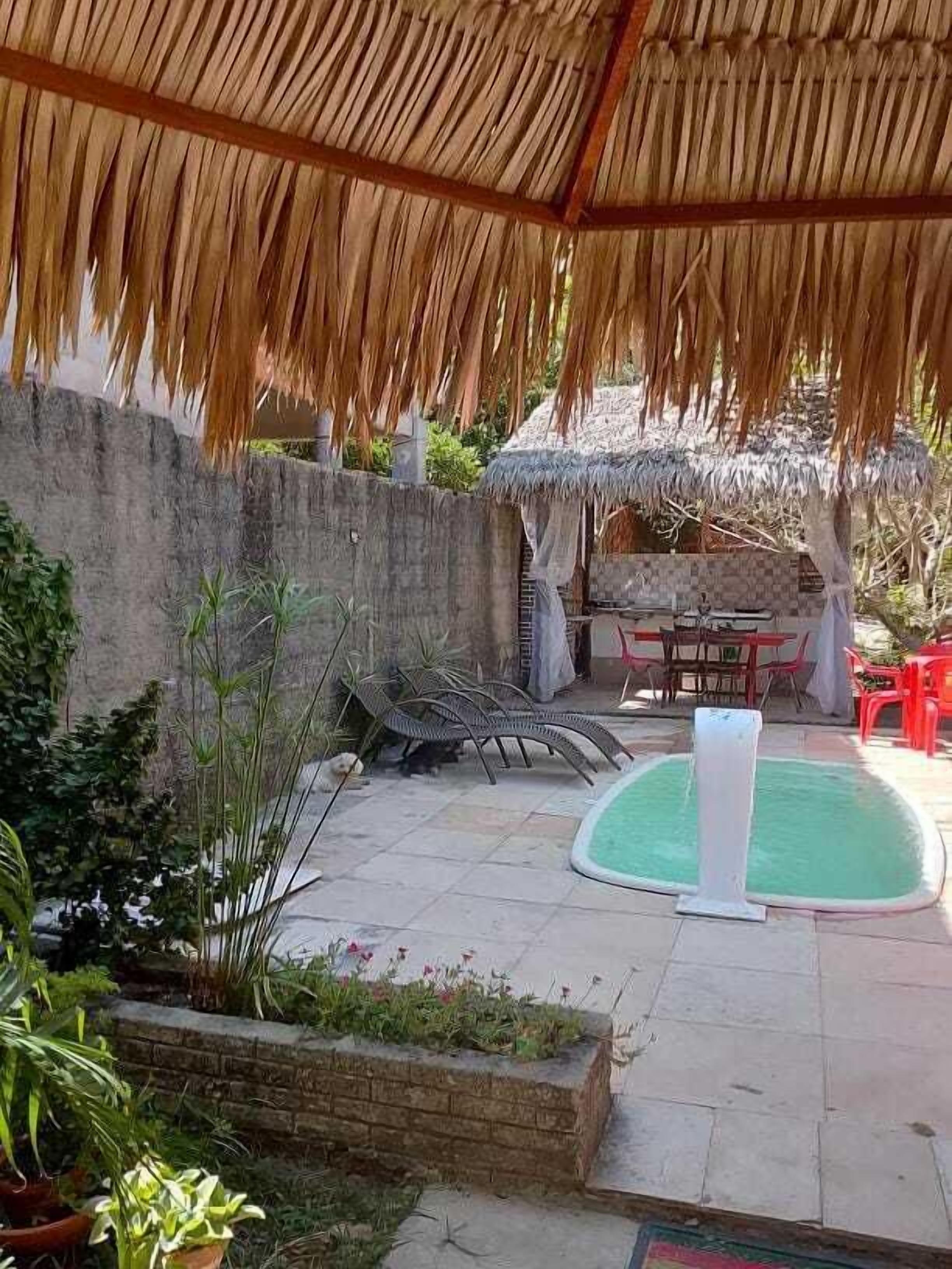 A covered outdoor area with a pool, seating, and a thatched roof structure.