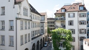 A narrow street with buildings on either side, featuring balconies and arched windows. - Paradeplatz / In Gassen Apartment by Airhome (Zürich)