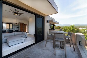 Relax in this open-plan living area with a large sofa and dining table for two, perfect for enjoying the surrounding landscape.