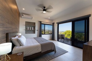 Relax in this serene space with a large bed, ceiling fan, and sliding glass door leading to a balcony with a view.