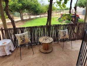 Relax in a charming outdoor setting with a round table and two cushioned chairs.