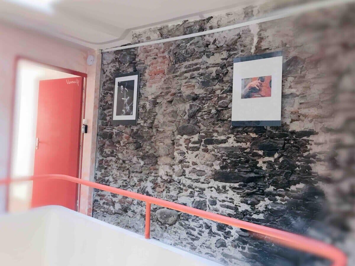 A staircase with a stone wall and two framed pictures.