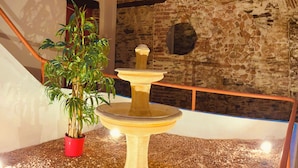 A stone fountain with a red pot and a bamboo plant beside it. - Résidence St Vincent (Collioure)