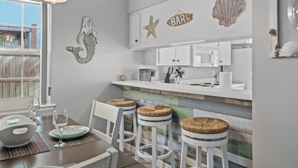 Una cocina con barra, armarios blancos e isla de madera.