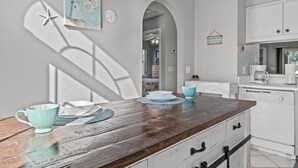Una cocina con encimera de madera, armarios blancos y vista al área de comedor.