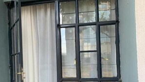 Una habitación con ventana, cortina y suelo de baldosas.