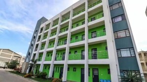 Un edificio de varios pisos con fachada verde y blanca, varios balcones y un techo plano.