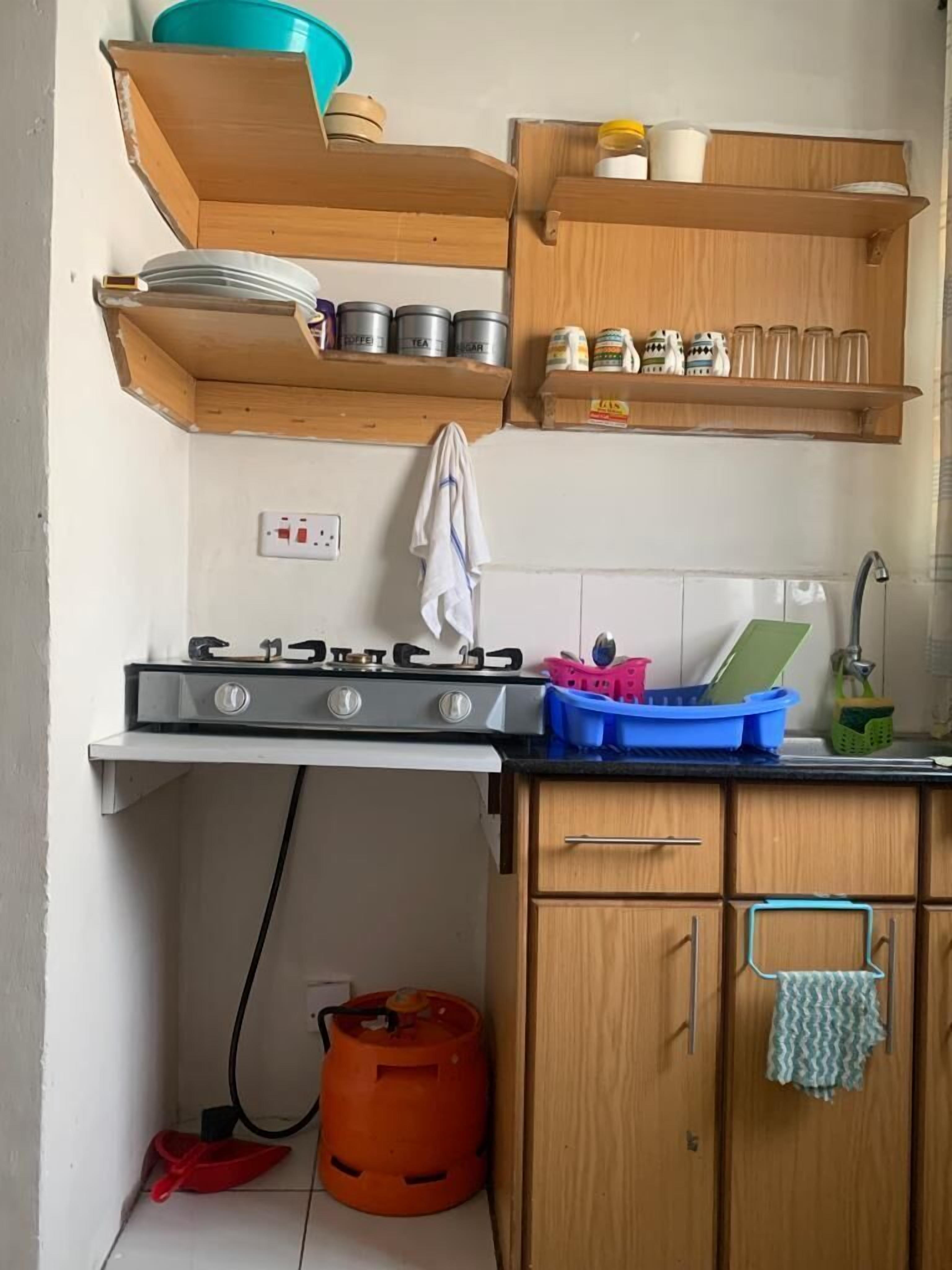 A compact kitchen with a gas stove, wooden cabinets, and a countertop with various kitchen items.