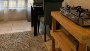 Una habitación con una mesa de comedor, sillas, un televisor montado en la pared y una estufa a gas.