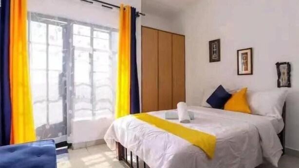 Una habitación de hotel con cama, cortinas, armario y ventana.