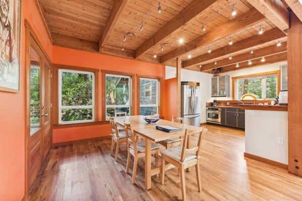 A modern kitchen with wooden cabinets, a central island, and large windows.
