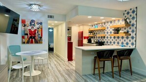 Una cocina moderna con barra, sillas blancas y una mesa de comedor de madera.