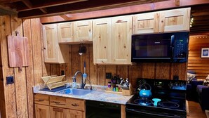 A compact kitchen with wooden cabinets, a microwave, a stove, and a dishwasher.