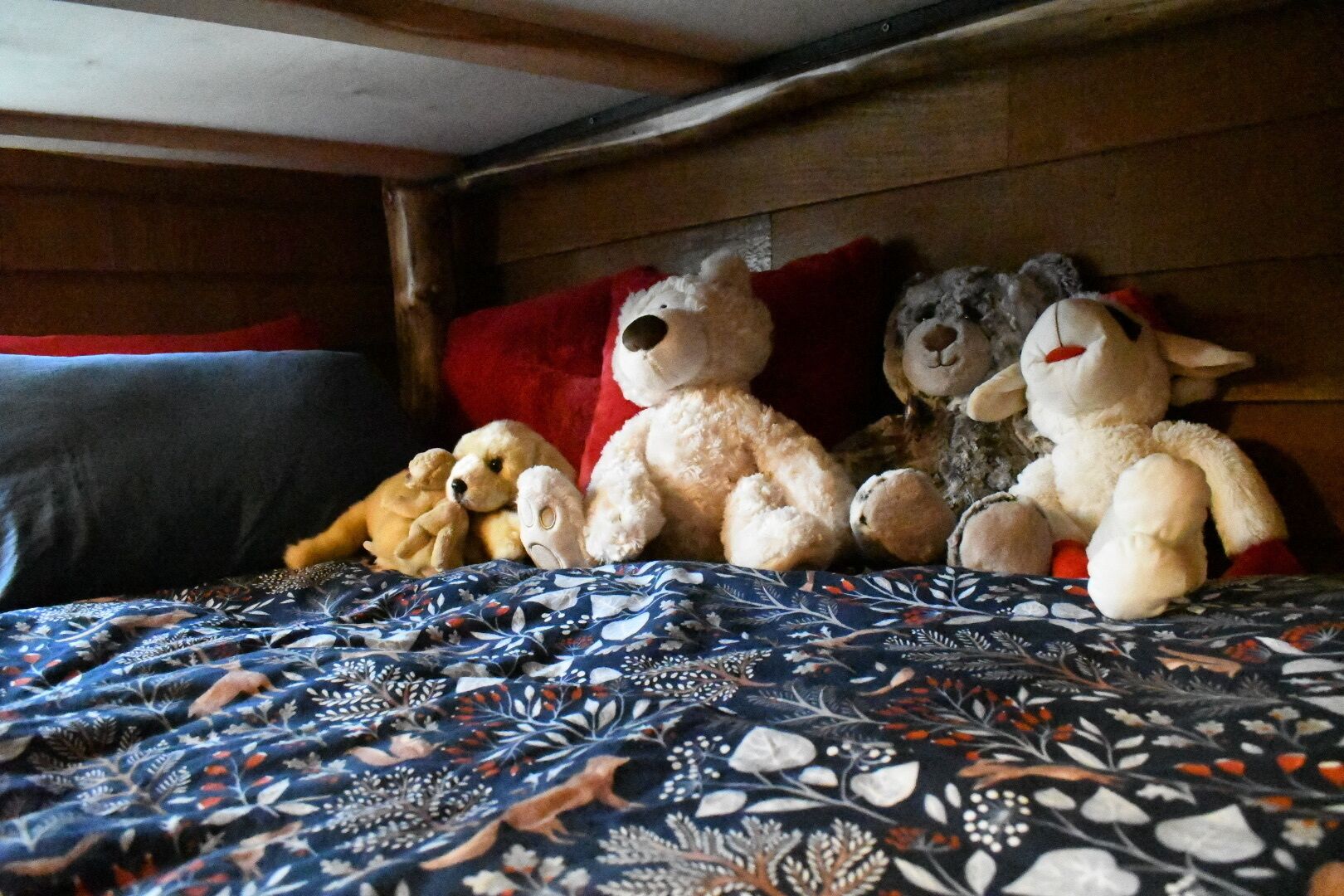 A bed with a patterned bedspread and multiple stuffed animals.