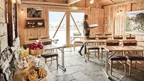 A wooden interior with tables and chairs, a stone floor, and a view through the door. - Utne Hotel (Ullensvang)