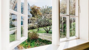 A view from a window with white frames, overlooking a garden with blooming trees and a white picket fence. - Utne Hotel (Ullensvang)