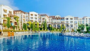 Un hotel con piscina, varios balcones y jardines exuberantes.