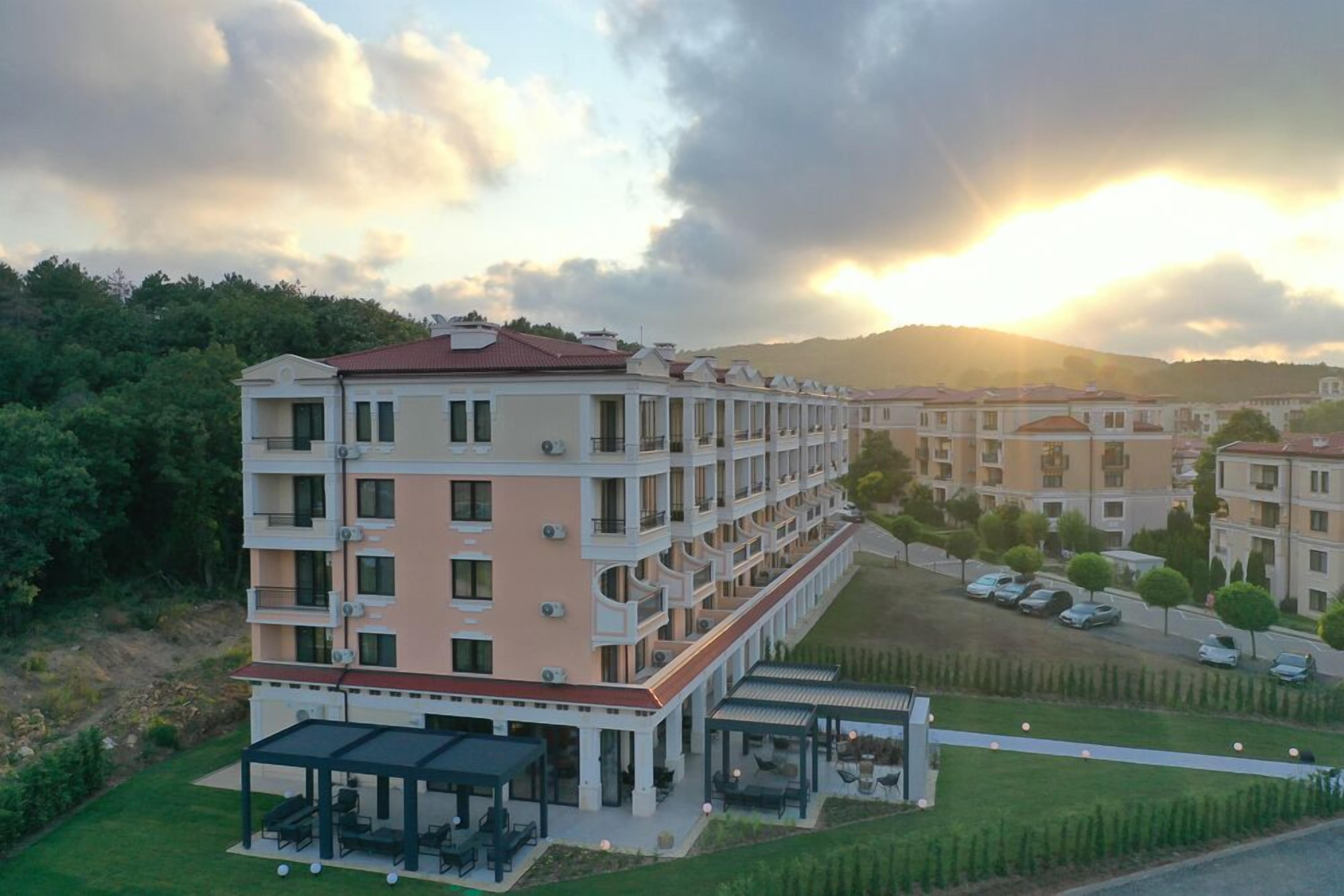 Un hotel de varios pisos con balcones, un área de estar techada al aire libre y un estacionamiento.