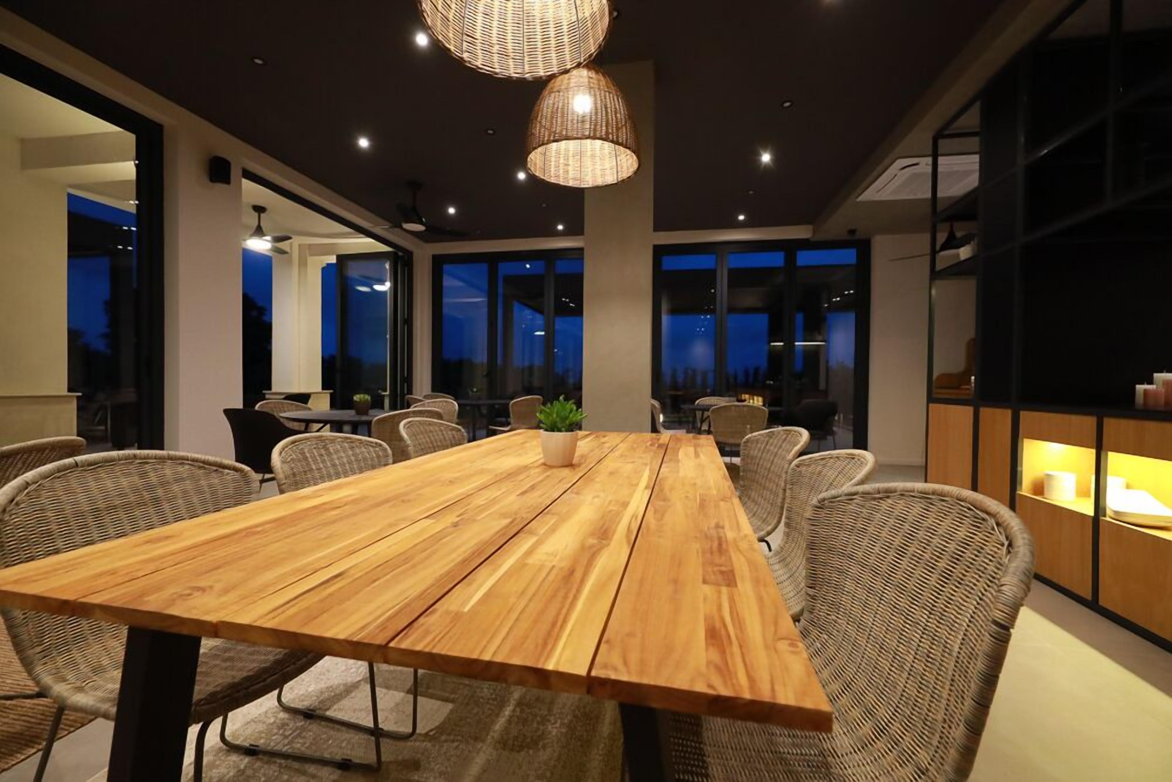 A modern dining area with a wooden table, wicker chairs, and pendant lighting.